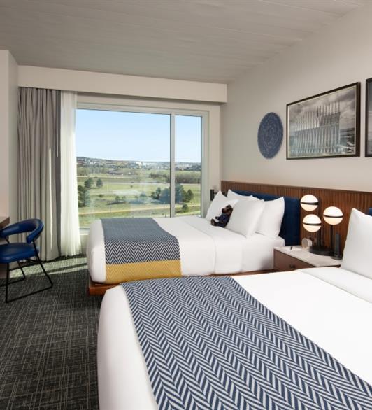 Two white beds next to each other, one has a brown bear stuffed animal on it