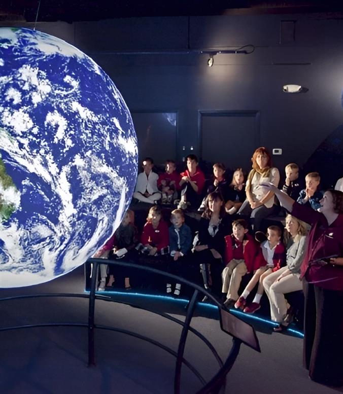 A teacher pointing at a globe of earth teaching students