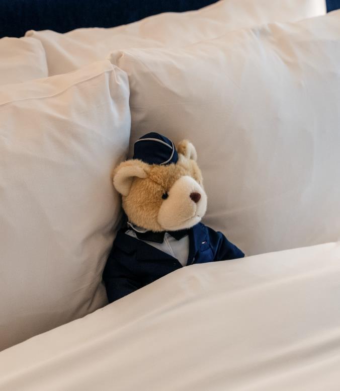 A teddy bear tucked into a bed