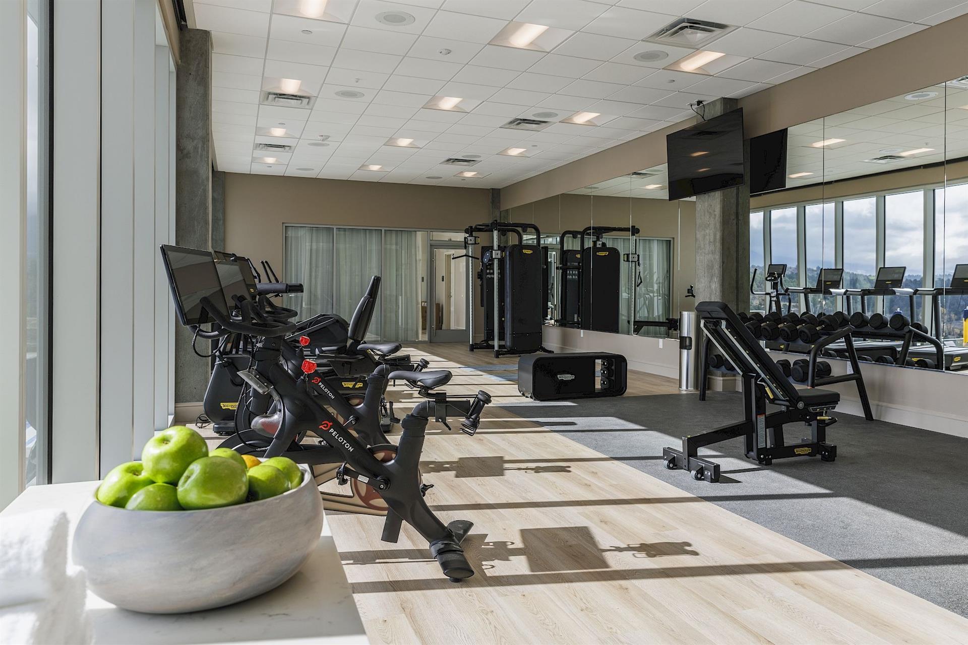State-of-the-art fitness center at Hotel Polaris featuring Peloton bikes, strength-training equipment, free weights, and floor-to-ceiling windows with scenic Colorado views.