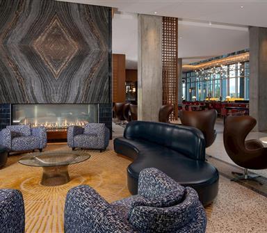 Hotel Polaris lobby lounge featuring a dramatic stone fireplace, contemporary seating, and an open-concept design connecting to the hotel's restaurant and bar with views of the Colorado landscape.
