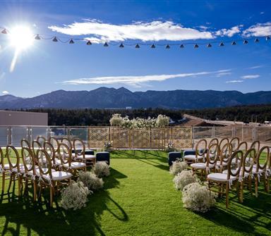 Rooftop wedding ceremony setup at Hotel Polaris featuring rows of gold chairs, white floral arrangements, and mountain views beneath a bright blue Colorado sky.